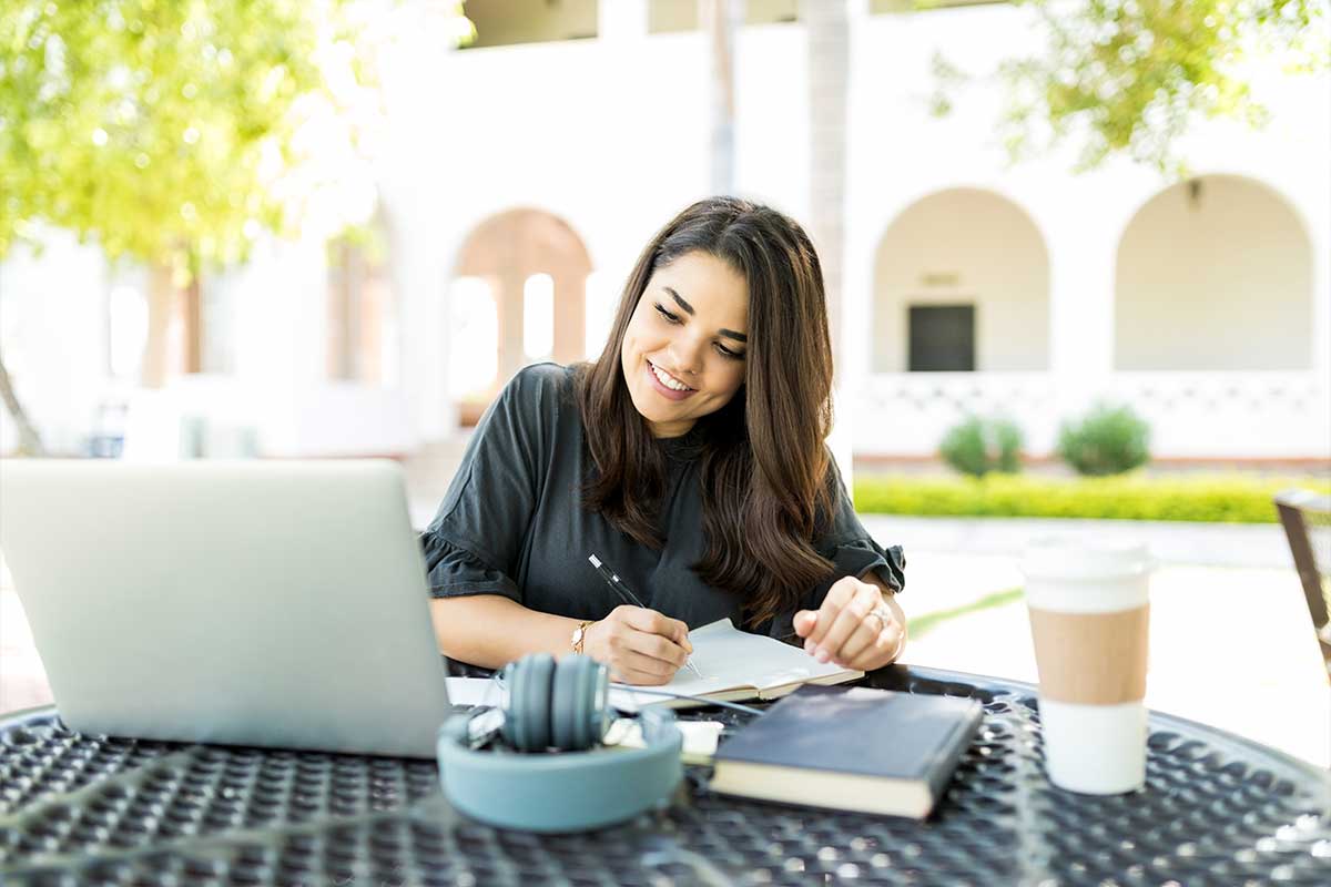 Woman learning online While Looking At Laptop In Garden